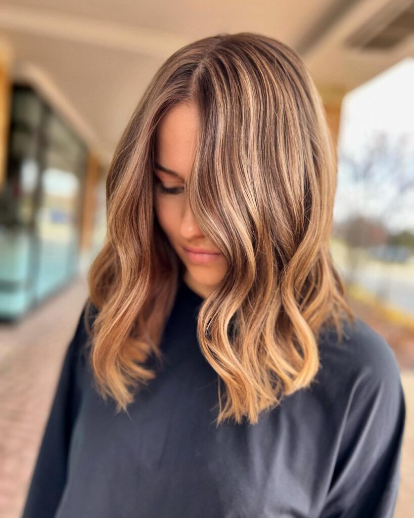 Brunette long bob with balayage highlights and soft waves through the lengths.