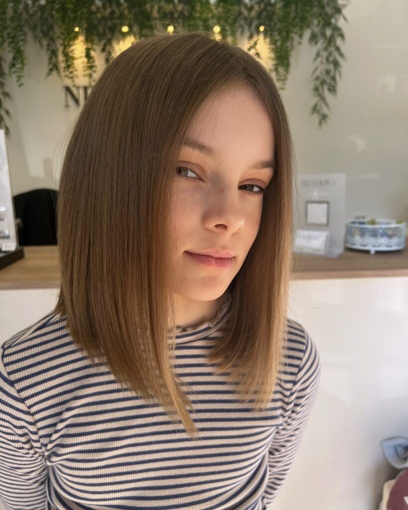 Angled brown long bob with longer front pieces and soft face framing layers.