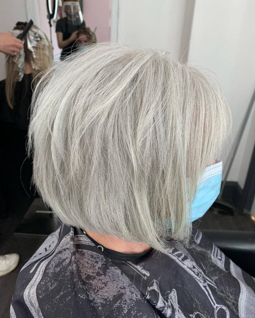 A side profile view of a woman over sixty with a platinum silver choppy bob featuring internal layers and wispy ends.