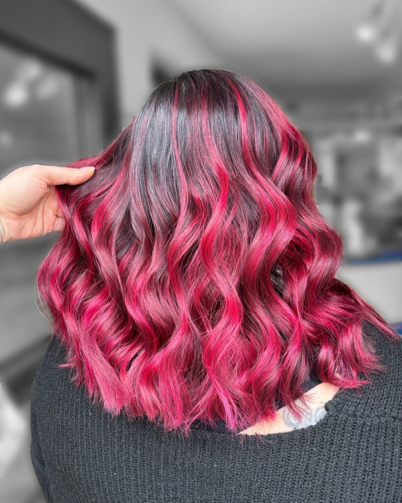 A side profile view of a woman showcasing a shiny ginger copper bob hairstyle with soft lived-in waves.