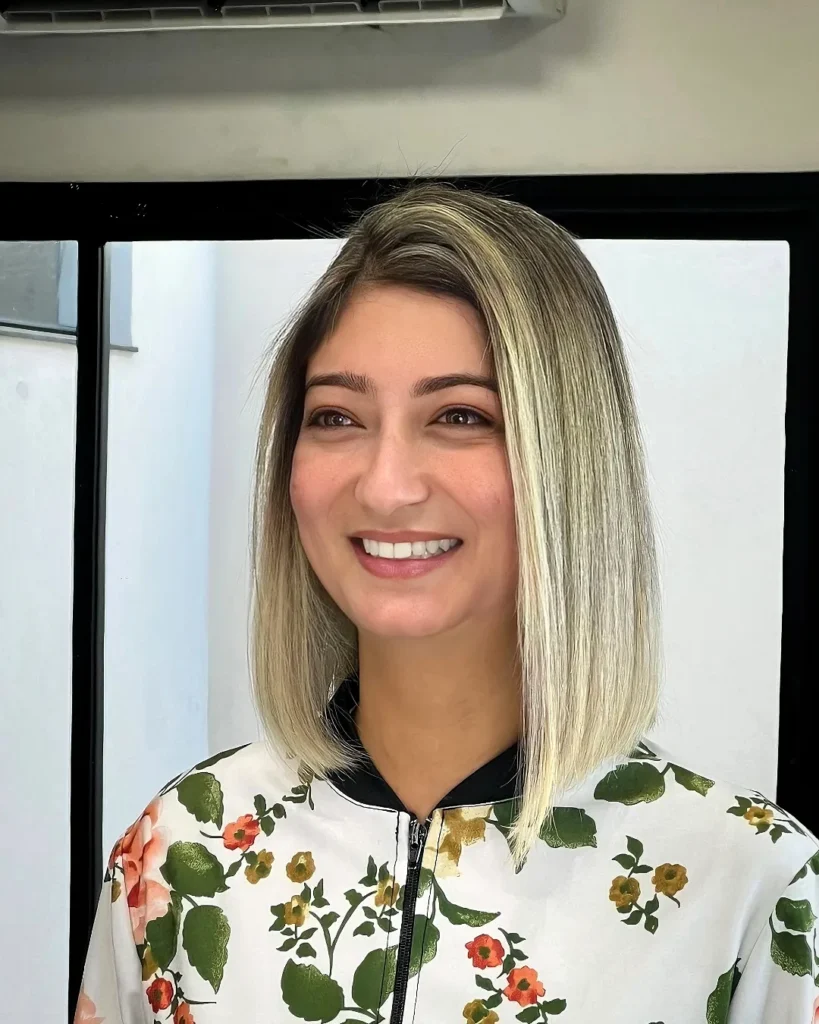 A blunt shoulder length blonde bob with brighter face framing highlights.