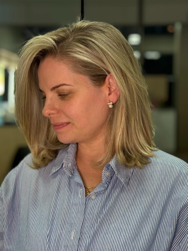 A layered shoulder length lob with a soft side sweep and warm blonde tones.