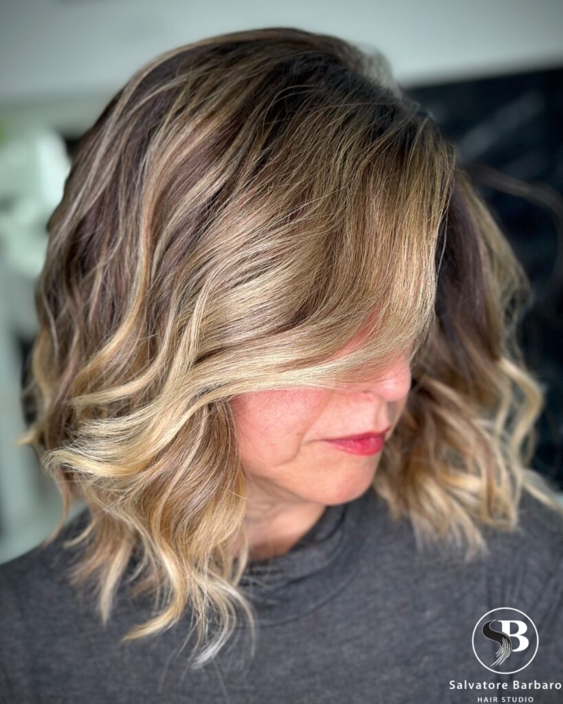 A wavy lob with a deep side part and soft blonde dimension.