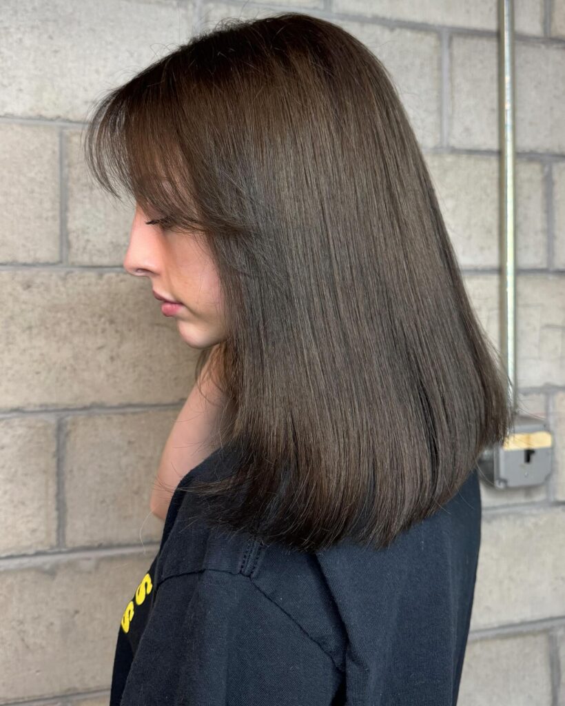 Smooth shoulder length lob with a side part and soft brown tones.