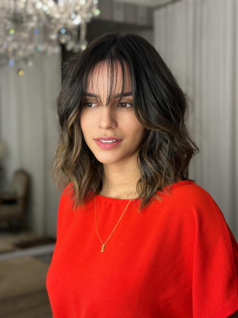 Wavy lob with wispy bangs and soft blended highlights.