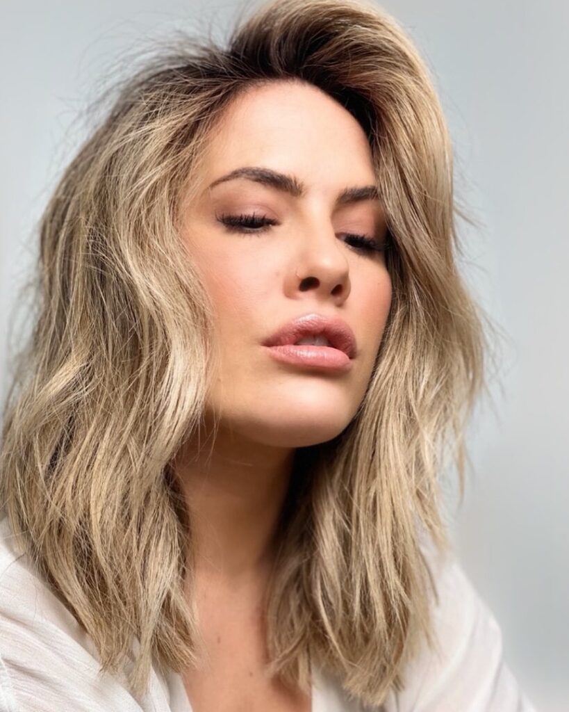 Layered blonde long bob with volume at the crown and soft textured waves.