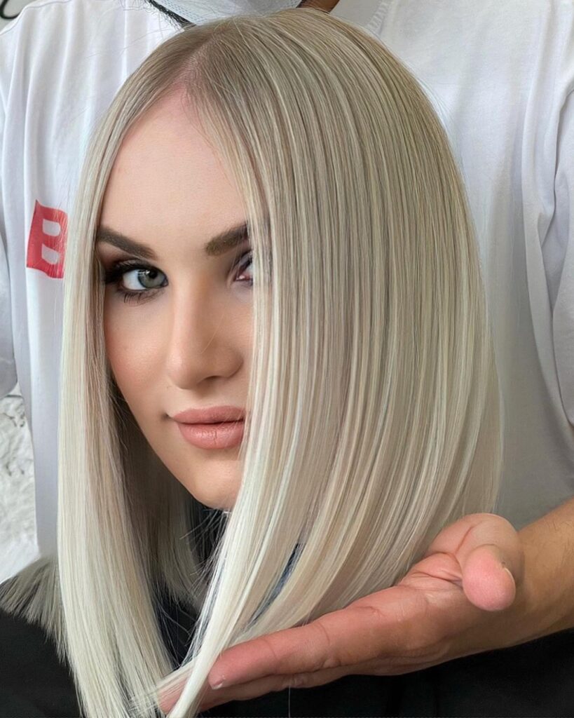 Straight platinum blonde long bob with a sleek finish and center part.