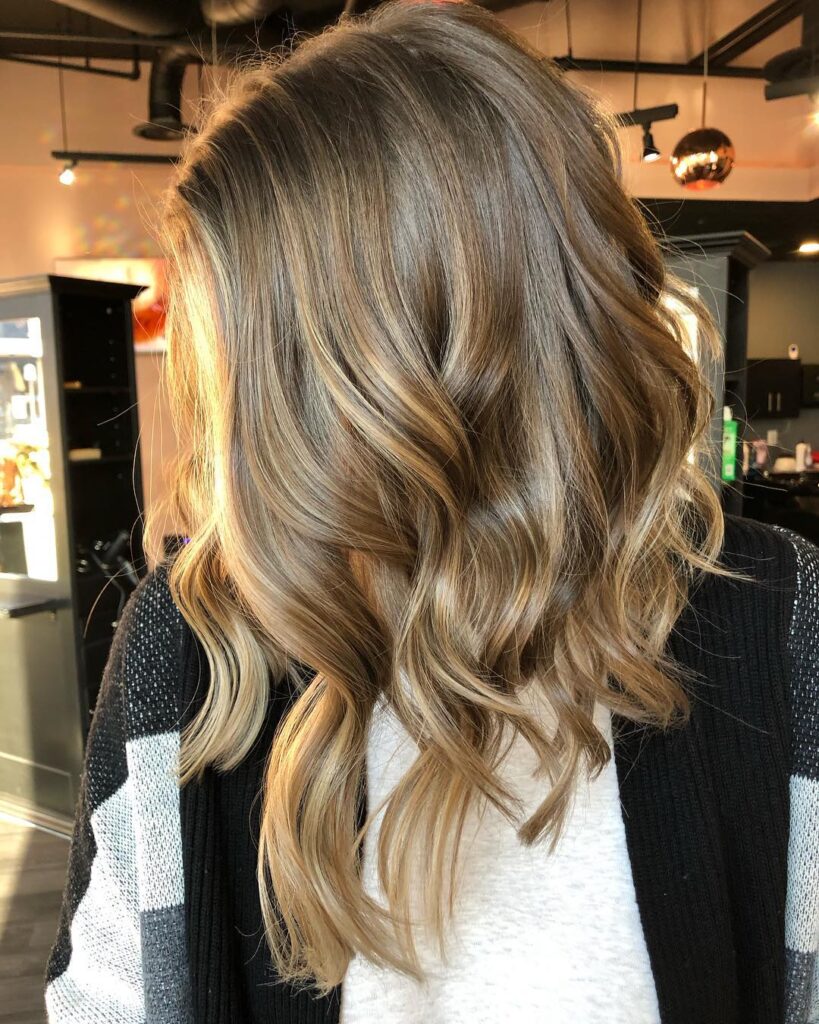 Textured blonde long bob with a side part and soft tousled layers.