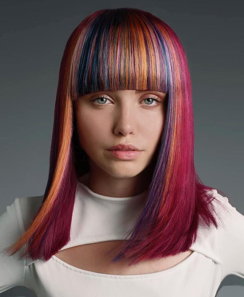 Straight long bob with blunt bangs and multicolored streaks in red and orange tones.