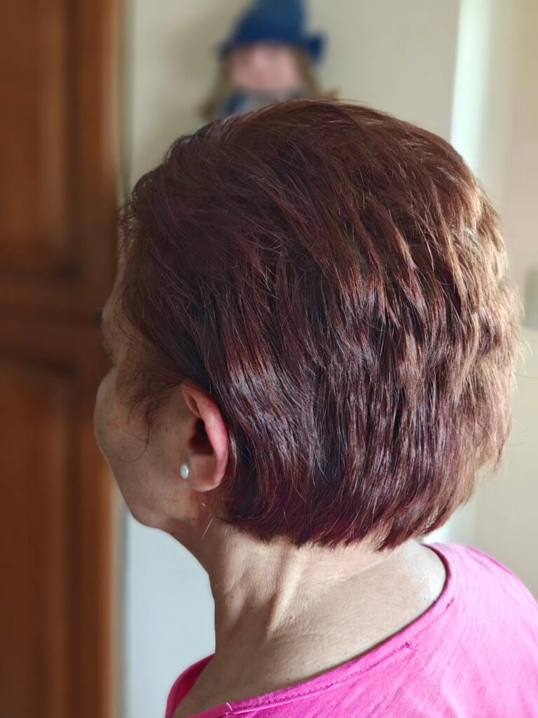 A woman with a short auburn layered bob styled with textured pieces and one side tucked behind the ear.