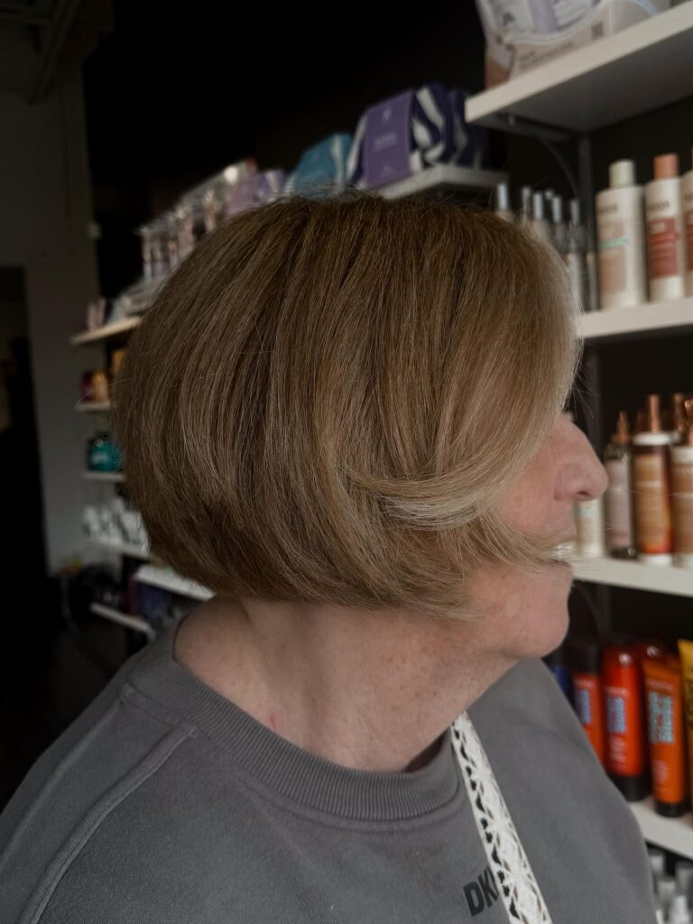 A woman with an ash-blonde, rounded, layered bob featuring a long side-swept fringe.