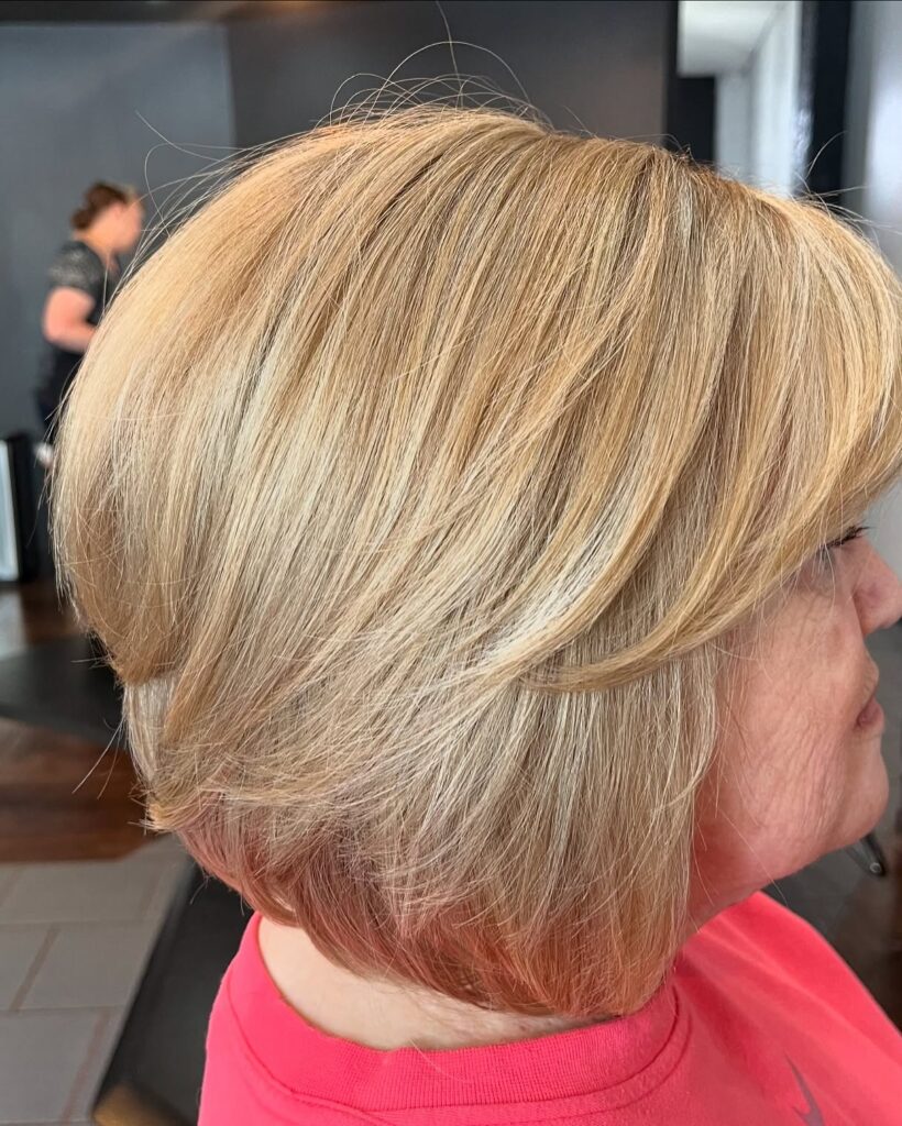 A woman showing a side profile of a jaw-length butter blonde bob with soft sweeping layers and a straight finish.