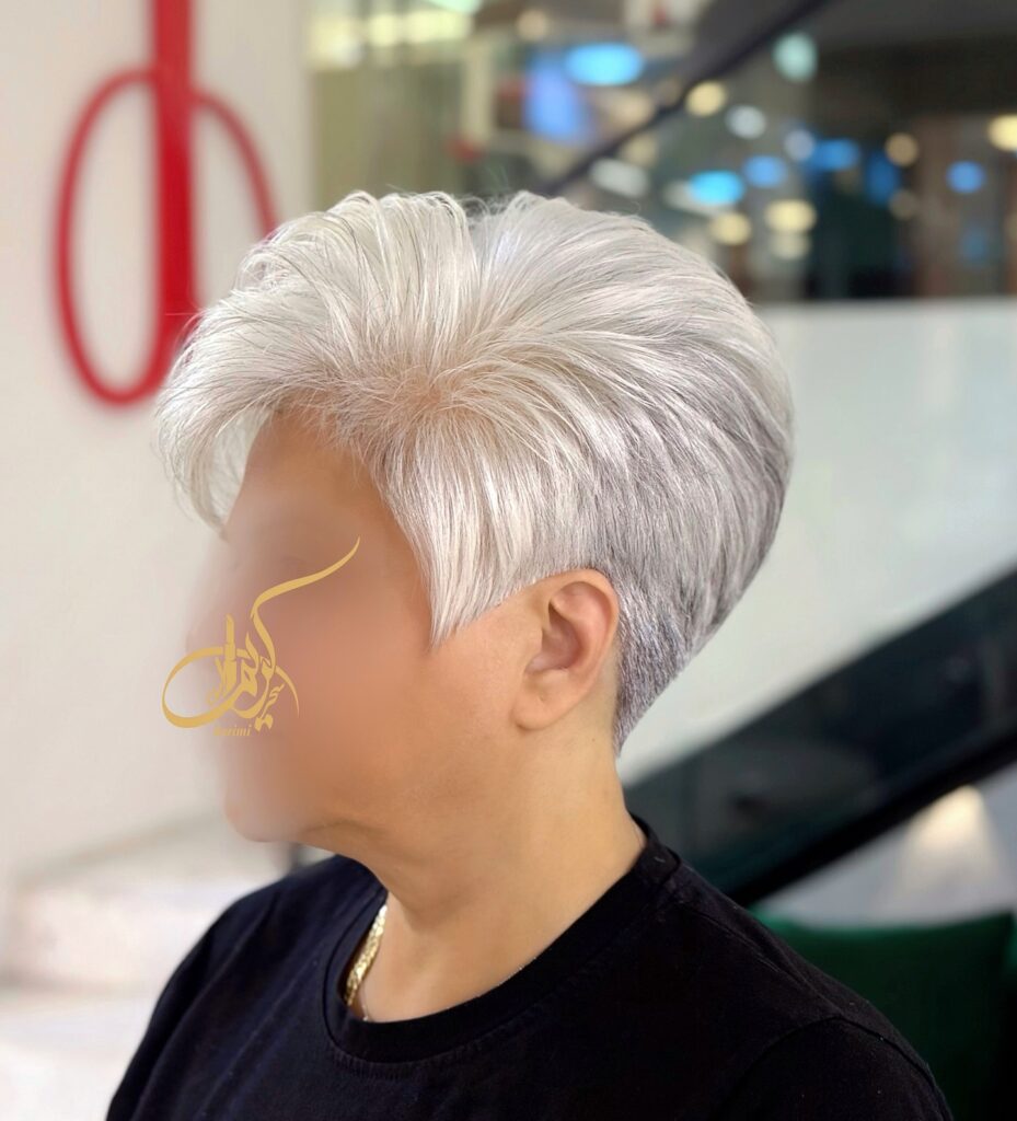 A woman over 60 with a luminous silver pixie cut featuring voluminous brushed back layers and precision tapered sides.