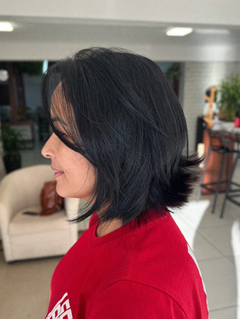 A woman in side profile showcasing a jaw length choppy raven black bob hairstyle with a gentle lift and playful flipped ends.