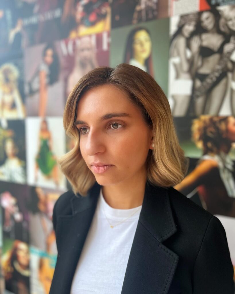 A woman looking slightly to the side showcasing a jaw length choppy caramel blonde bob hairstyle styled with soft elegant waves and a gentle lift.
