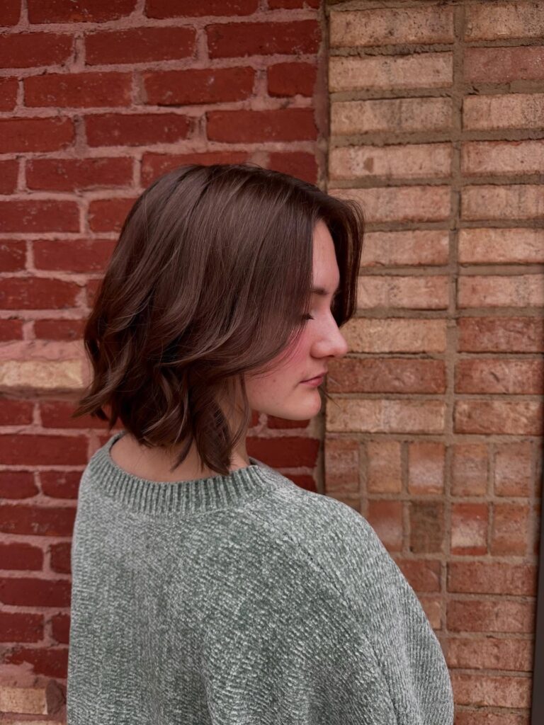 Short brunette layered bob with loose waves and soft textured movement.