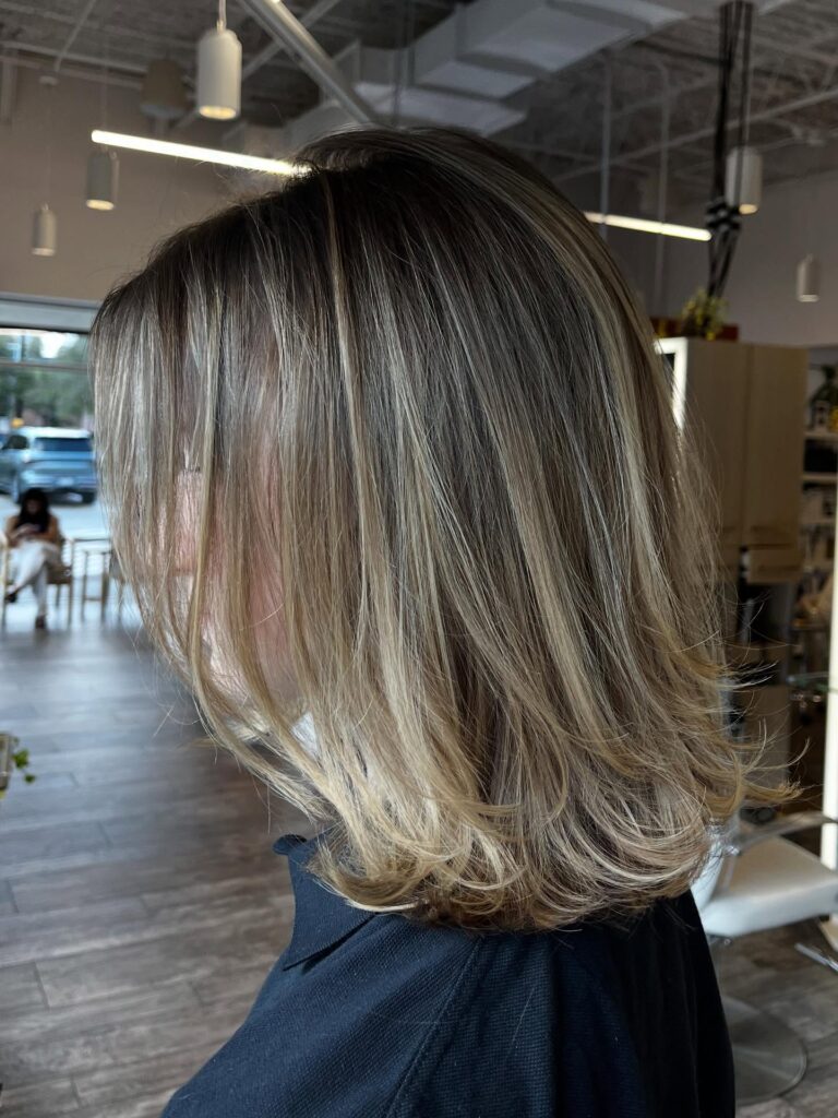 Shoulder length blonde layered lob with feathered ends and dimensional highlights.