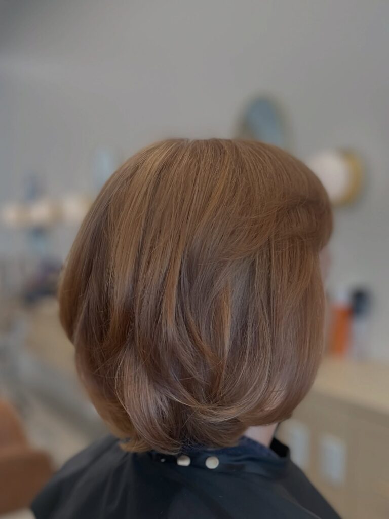 Rounded cinnamon brown layered bob with soft volume and curved under ends.