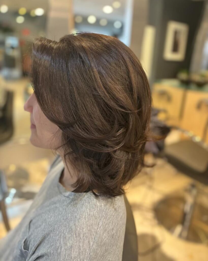 Medium brunette layered bob with feathered volume and softly curled ends.