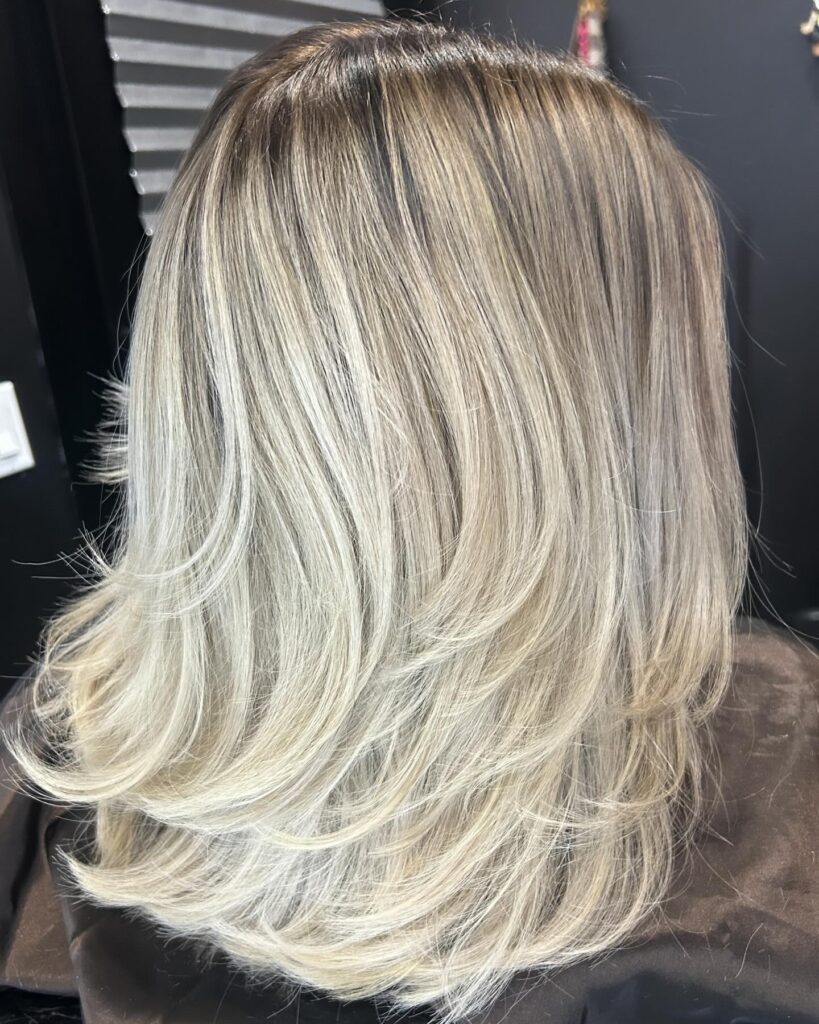 Feathered ice blonde layered bob with soft flipped out ends and dimensional color.