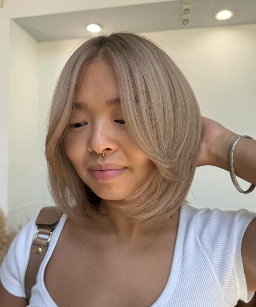 Rounded beige blonde layered bob with smooth face framing layers and soft curved ends.