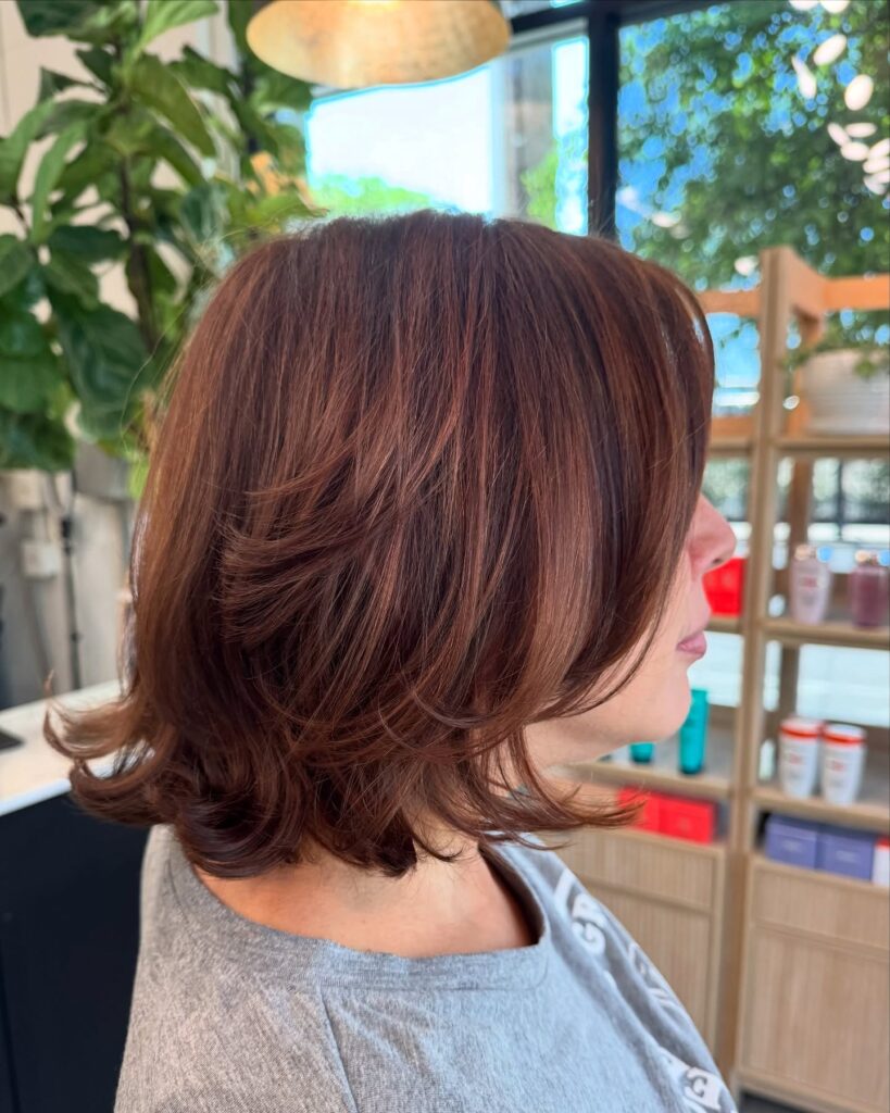 Rounded layered bob with voluminous soft layers and warm chestnut brown color.