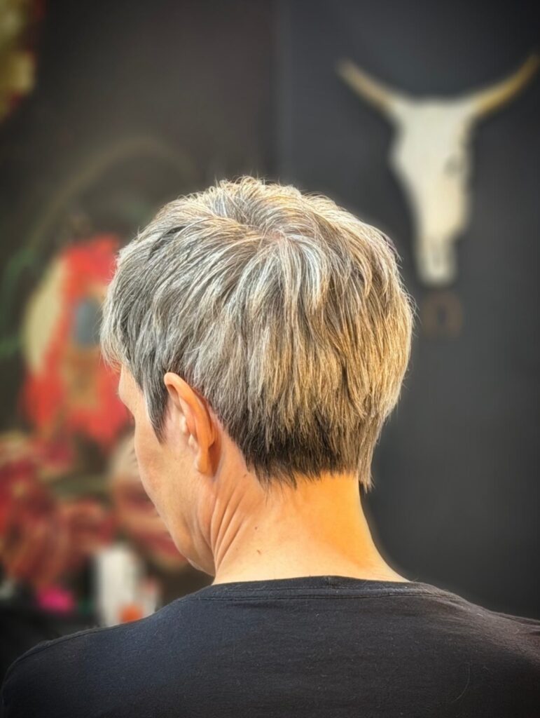 Short silver pixie haircut with textured layers and a tapered back.