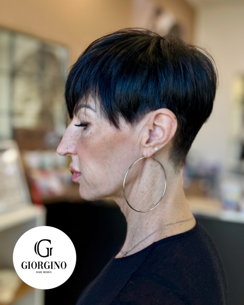 Sleek black pixie haircut with a tapered undercut and long side swept fringe.