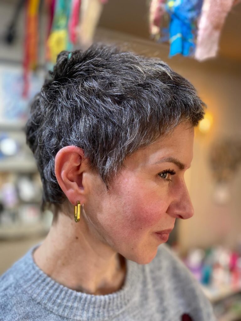 
Short salt and pepper pixie haircut with textured layers and soft crown volume.
