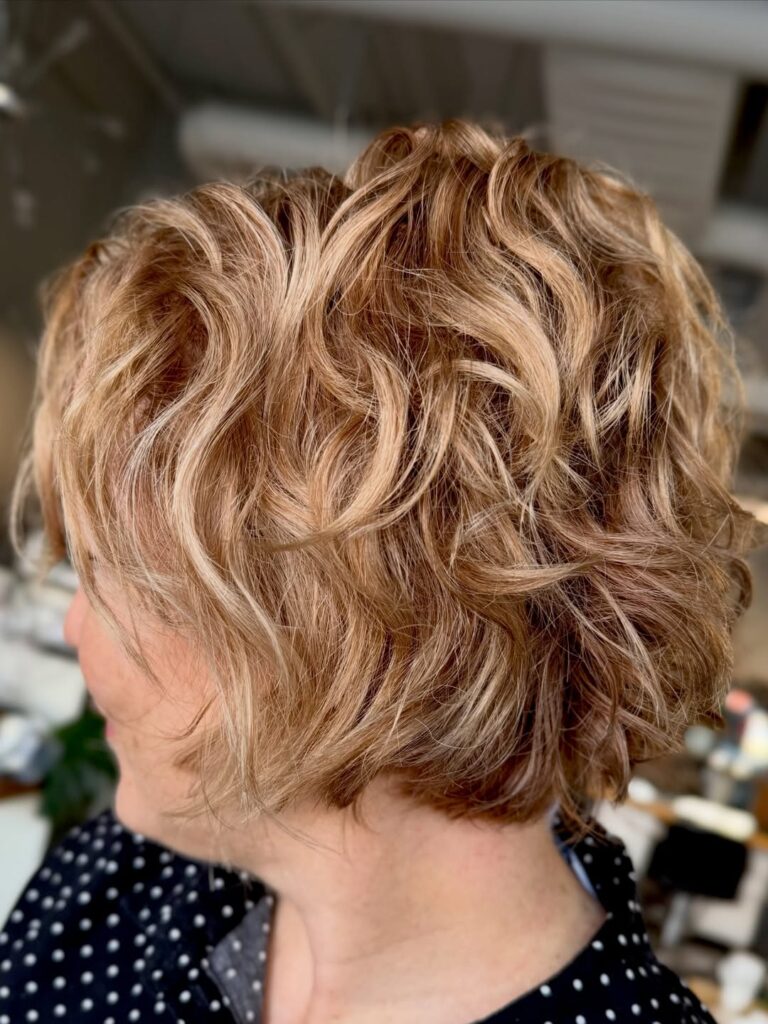 Layered blonde wavy pixie bob with soft texture and dimensional highlights.