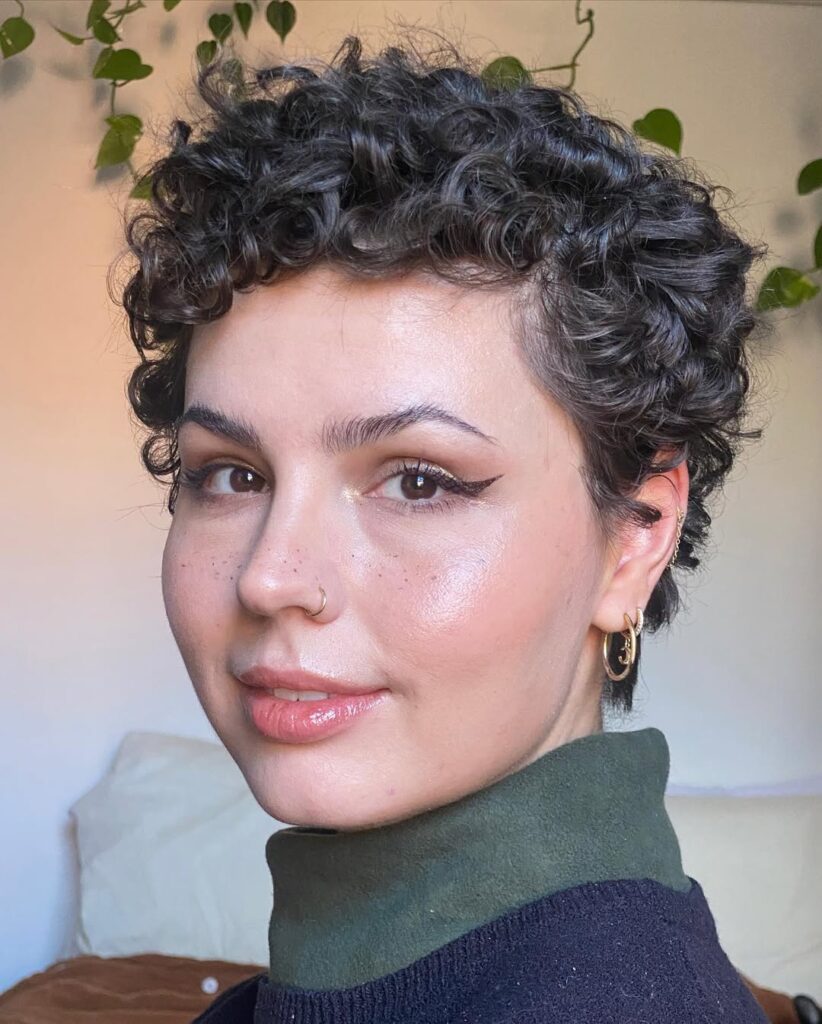 Classic short curly pixie haircut with rounded layers and soft brunette curls.