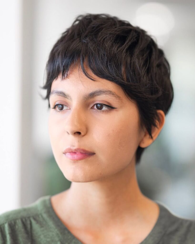 Dark textured pixie haircut with choppy layers and soft piecey bangs.