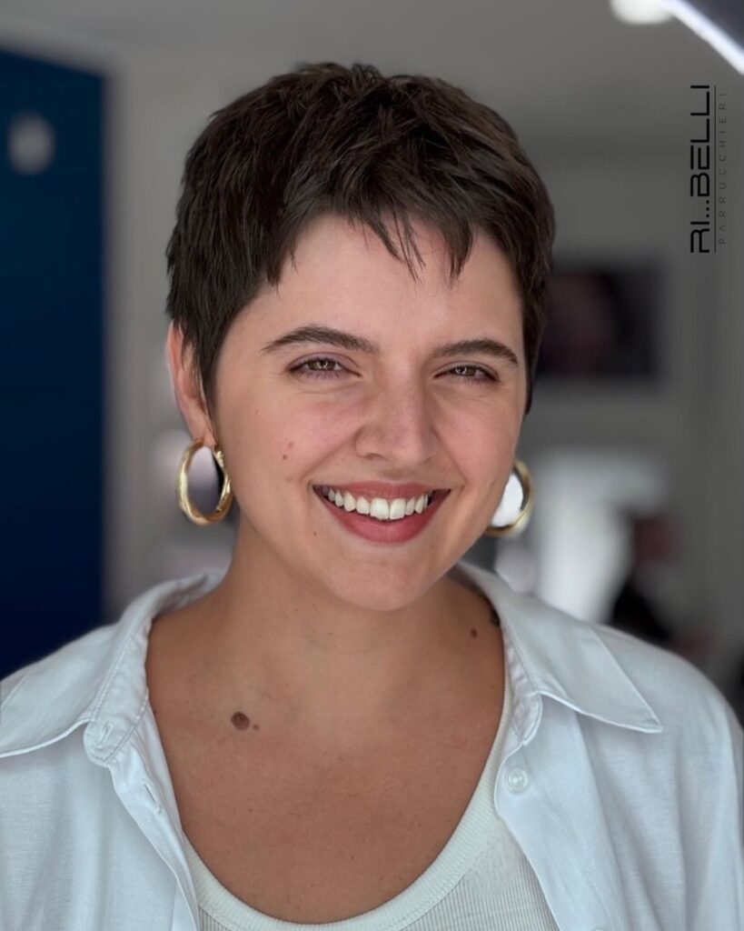 Dark textured French pixie haircut with short feathered bangs and cropped layers.
