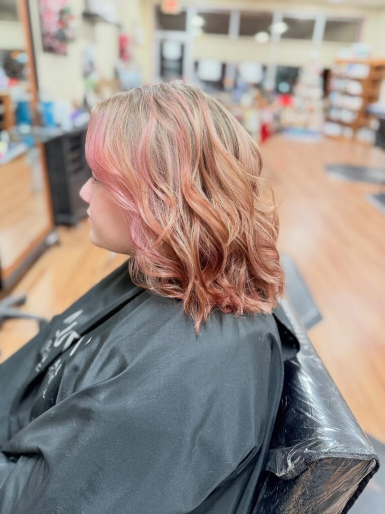 A rose gold wavy bob with soft pink highlights and textured layers.