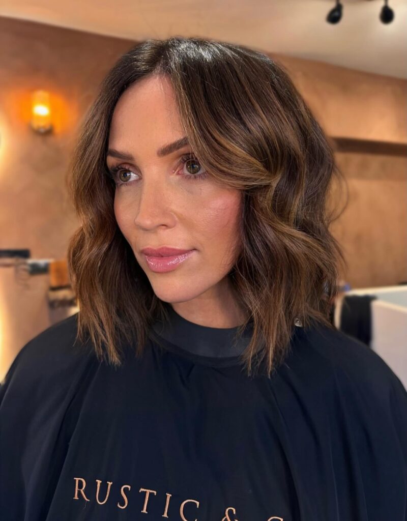 A softly waved brunette choppy bob with face framing layers and textured ends.
