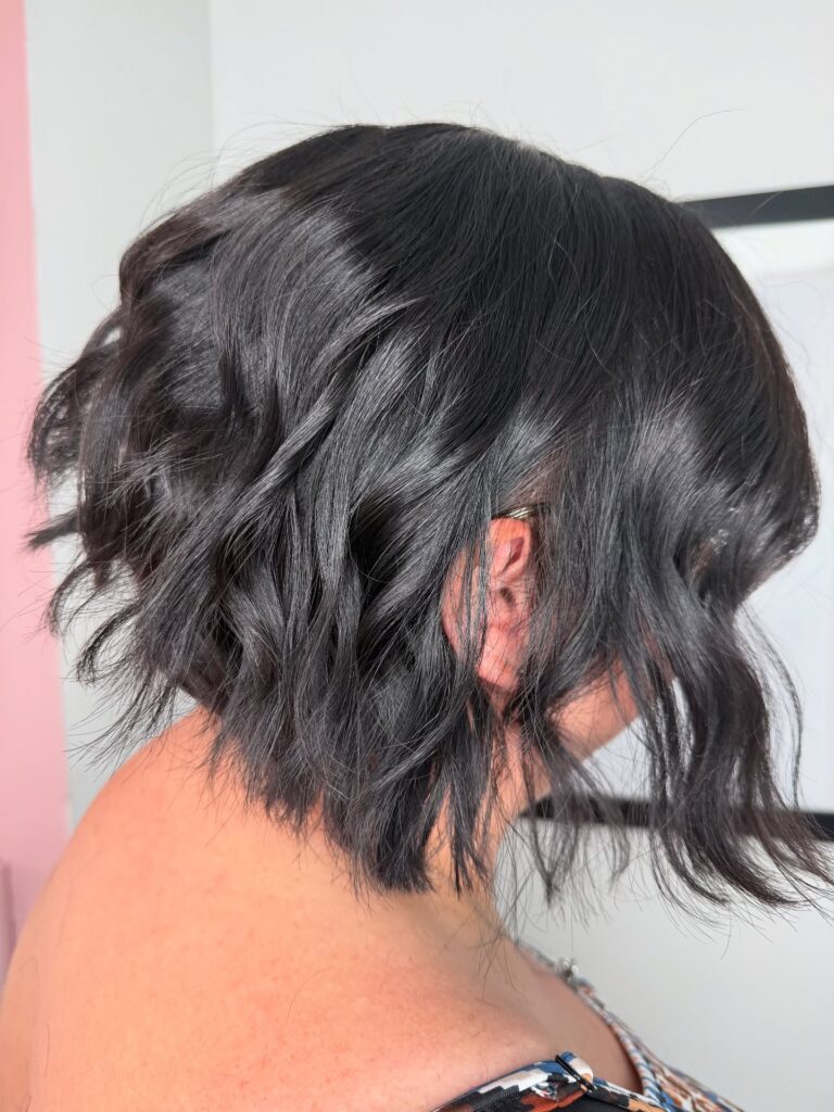A jet black tousled bob with loose waves and choppy textured ends.