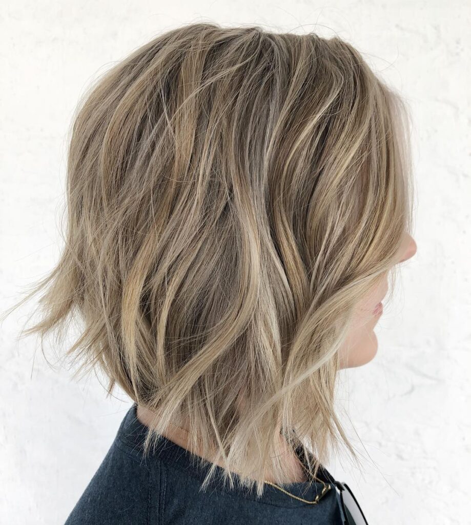 A beige blonde choppy bob with piecey layers and soft textured waves.