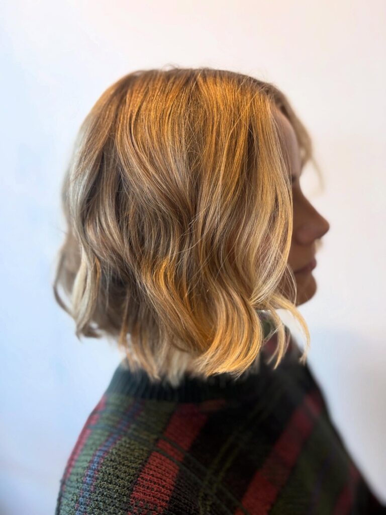 A golden blonde wavy bob with soft choppy layers and loose texture.