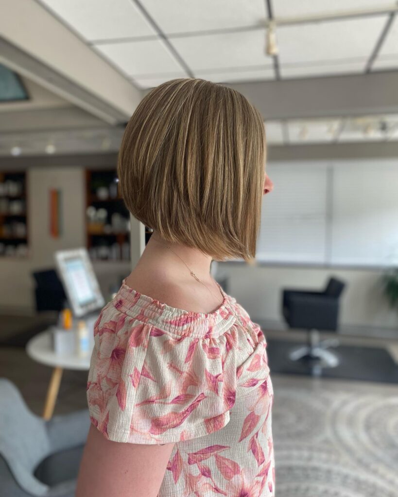 Angled brunette bob with blonde highlights and sleek smooth layers.
