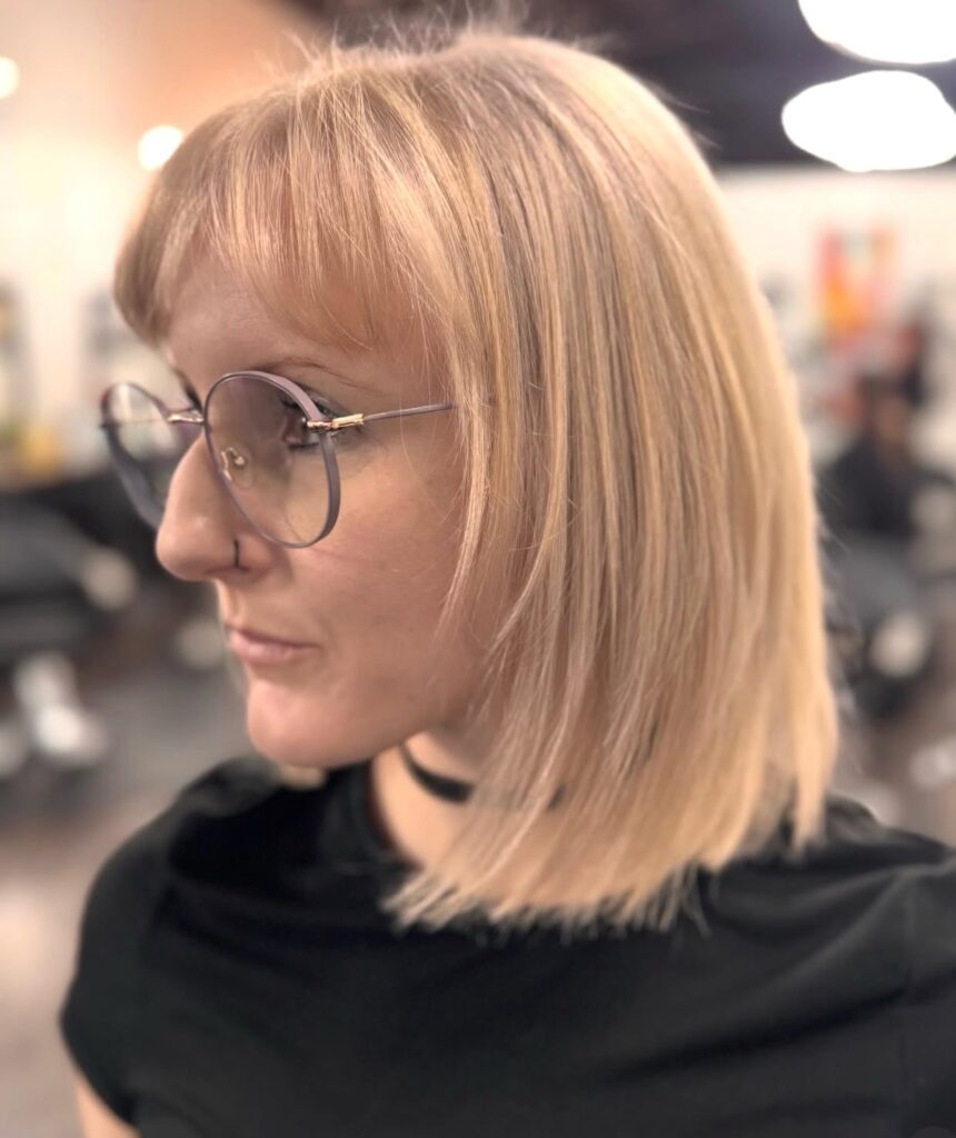 Smooth blonde chin-length bob with wispy bangs and subtle layers.