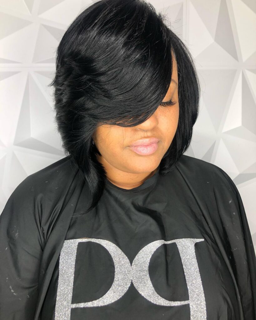 A jet-black layered bob with dramatic side-swept styling and soft stacked layers.