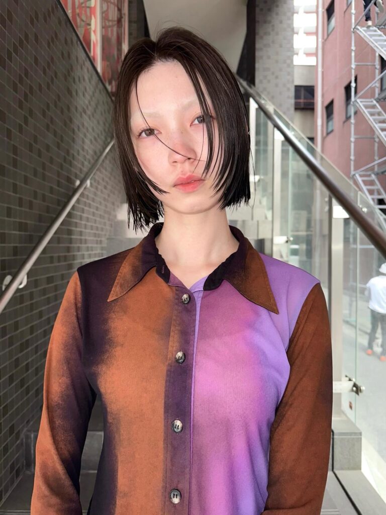 A sleek black blunt layered bob with wet-look styling and a center part.
