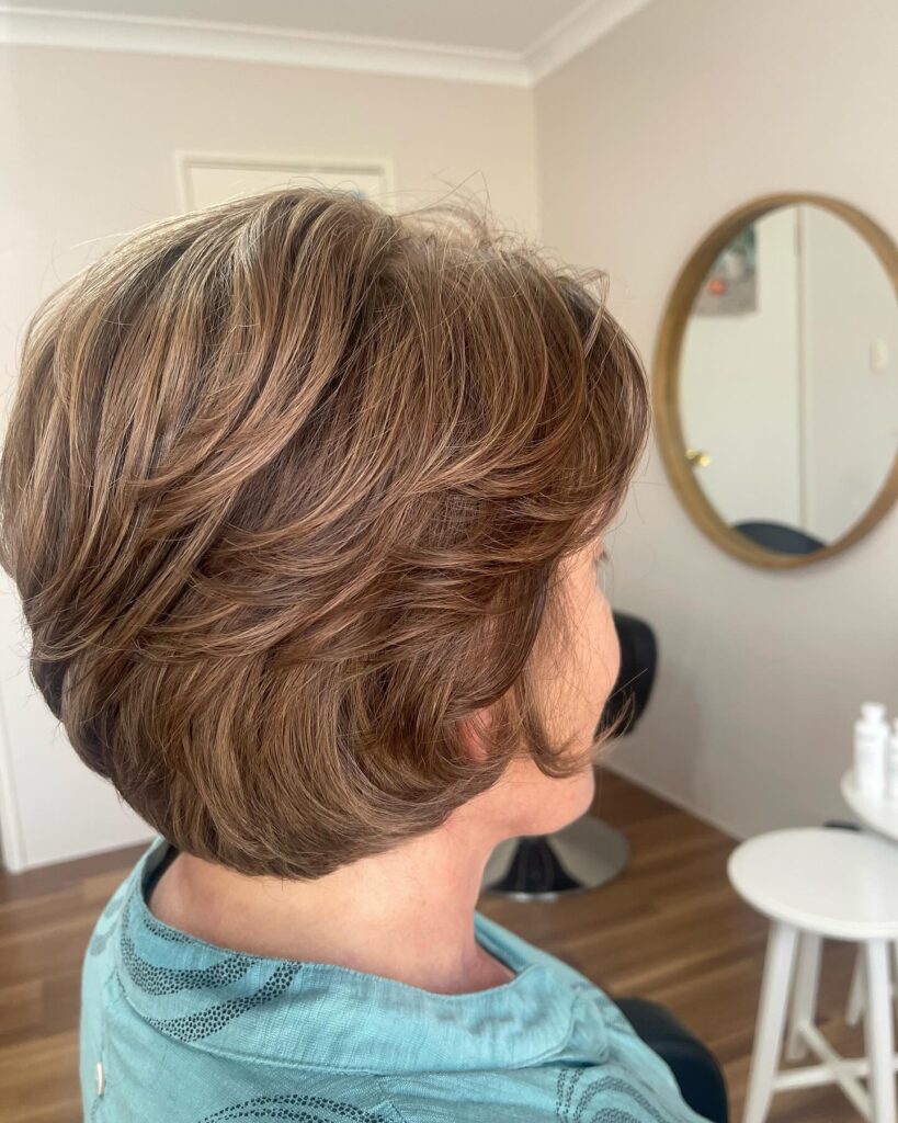 A feathered brunette bob with soft layered volume and warm mocha brown dimension.