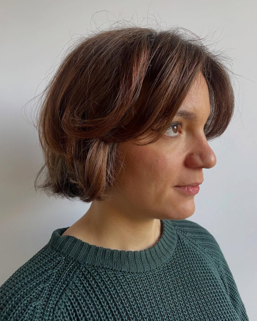 A chin-length brunette bob with curtain bangs and softly flipped layers.