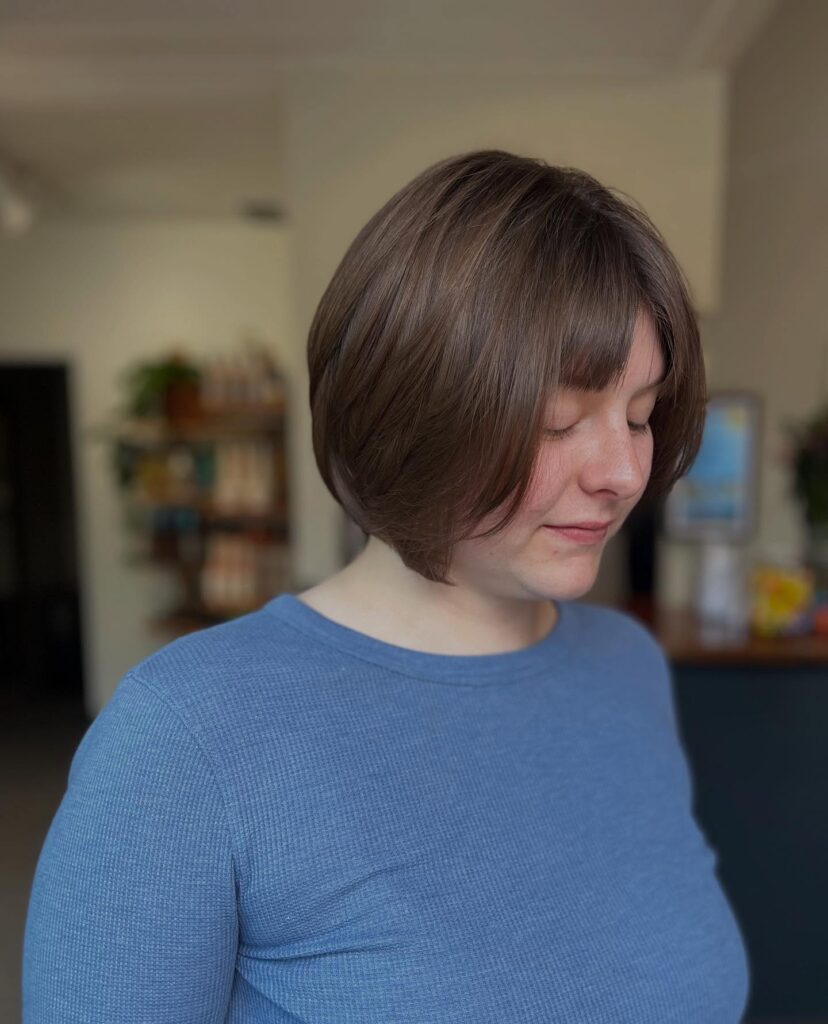 A rounded brunette layered bob with glossy volume and subtle dimensional highlights.