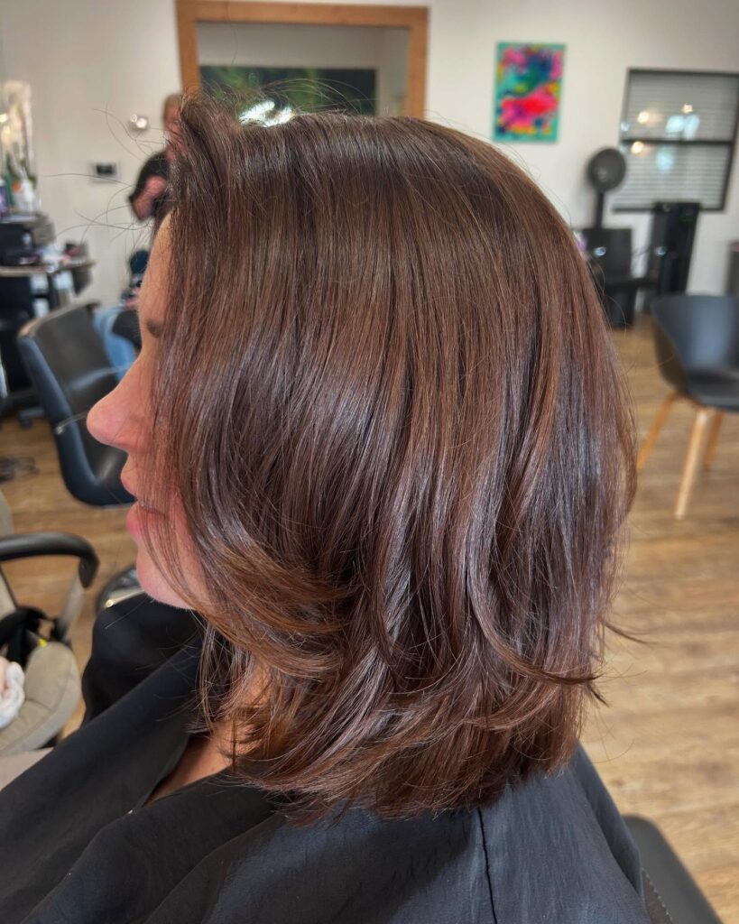 A shoulder-length brunette lob with soft layers and loose textured waves.