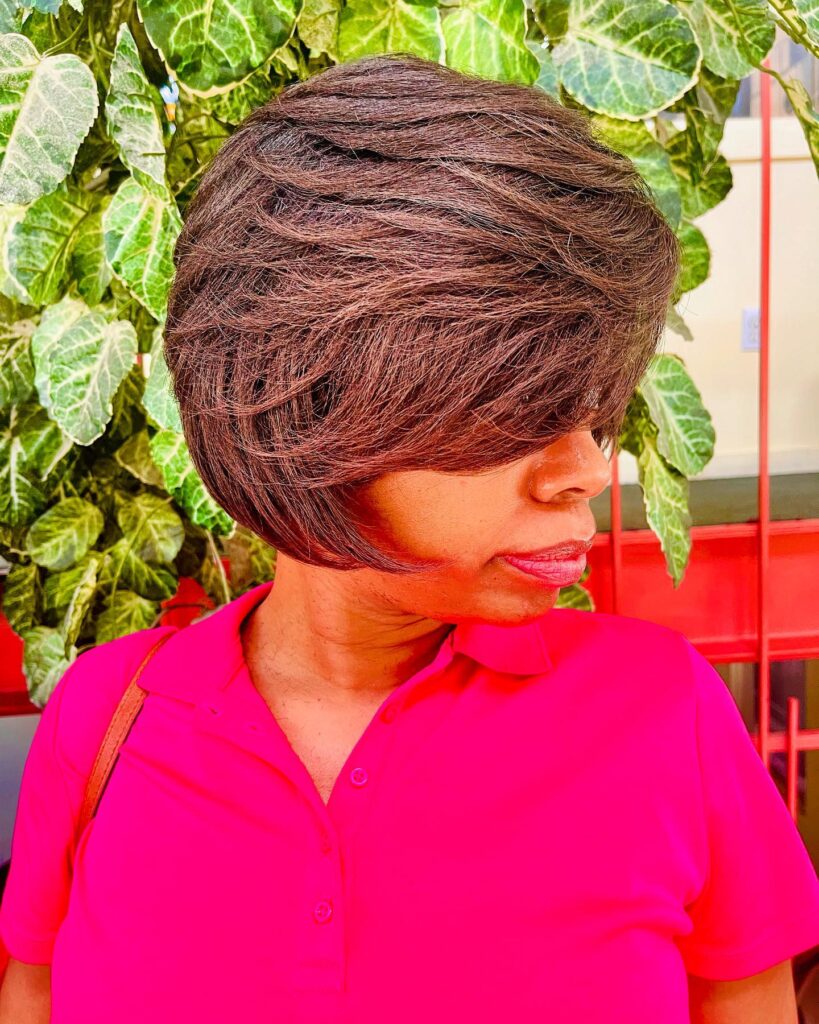 A voluminous brunette layered bob with side-swept fringe and a rounded shape.
