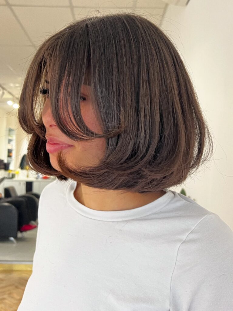 A rounded espresso brunette bob with a full fringe and curved layered volume.