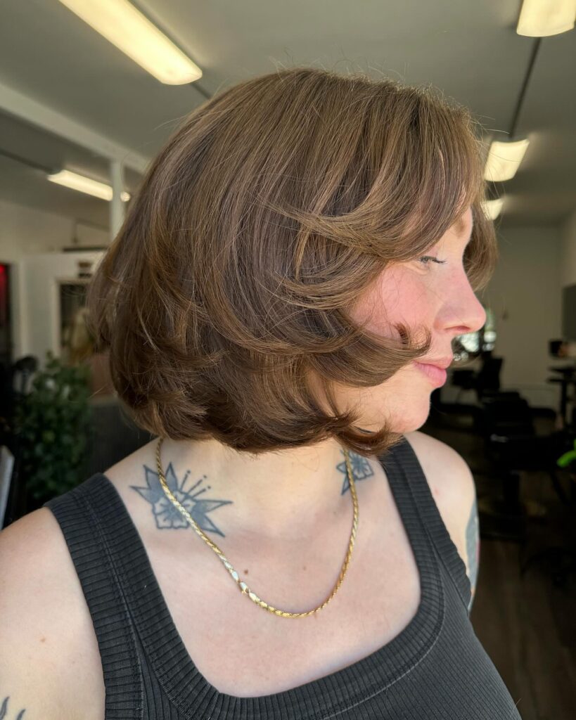 A feathered brunette bob with flipped layers and caramel dimensional highlights.