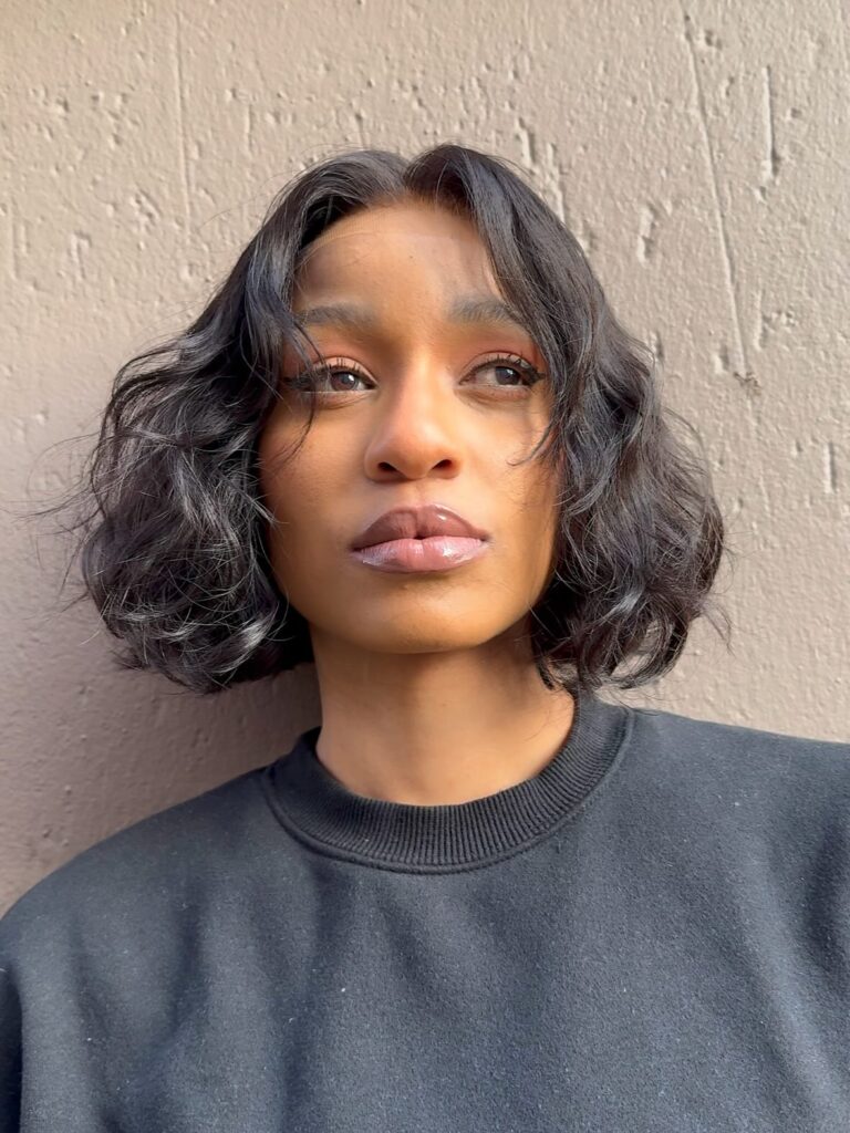 Dark chin-length bob with soft waves and a center-parted layered shape.